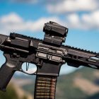 An assault rifle with mountains and sky in the background