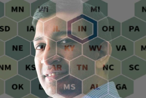A man's face appears behind a semi-transparent table with letters.